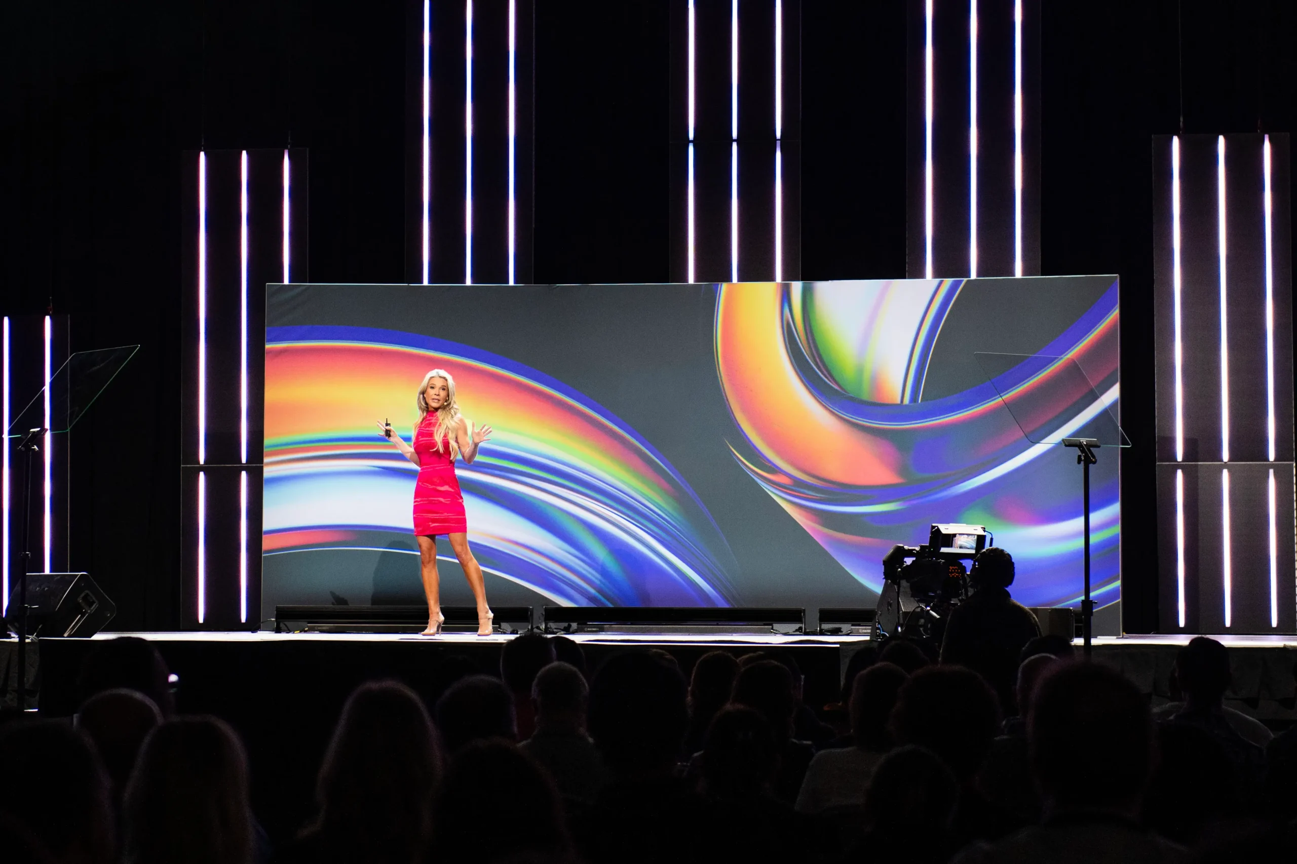 Jenn Drummond in a pink dress delivering a keynote speech
